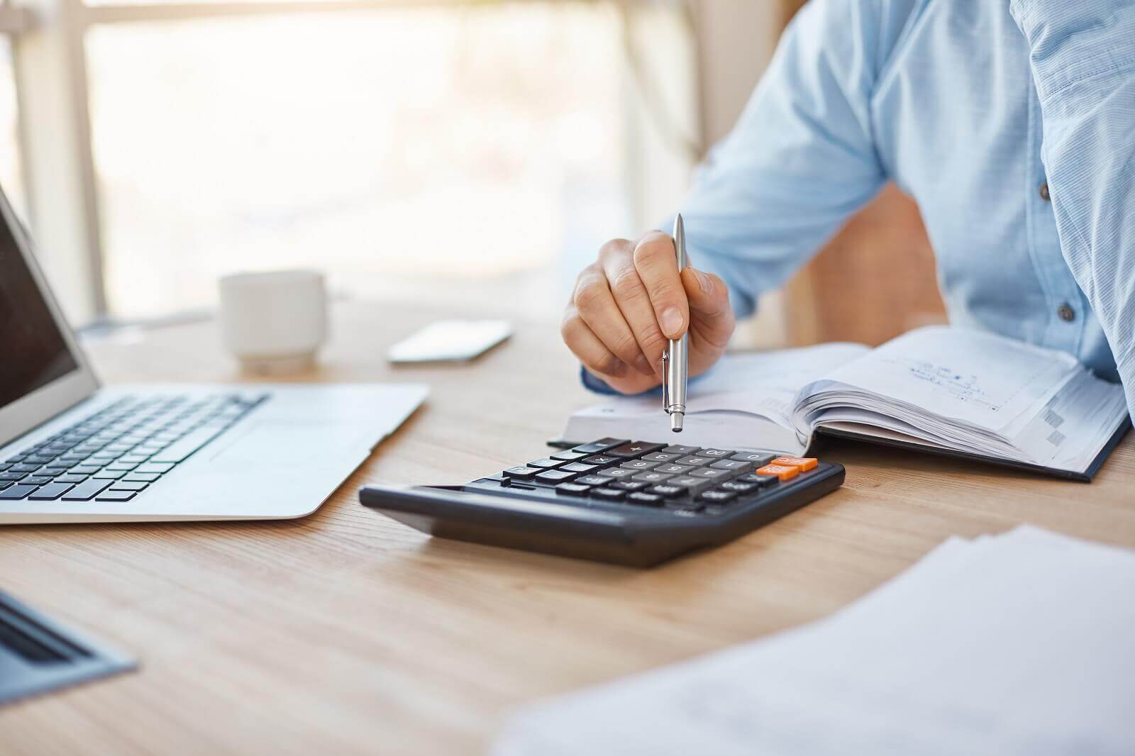 pessoa usando calculadora e notebook, fazendo contabiliade para oficina mecanica